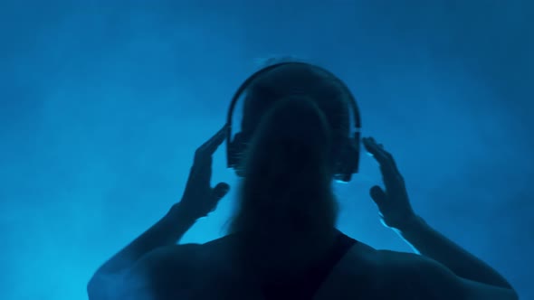 Silhouette of Female Dj in Headphones on Dark Background 