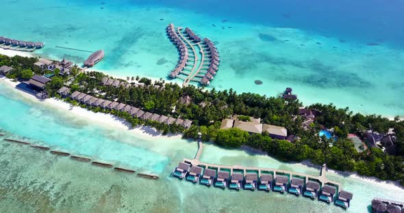 Bungalows over turquoise water of lagoon around tropical island, connected by wooden piers with whit