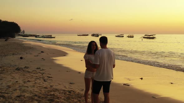 Man and woman sunbathing on marine seashore beach break by aqua blue ocean with bright sand backgrou