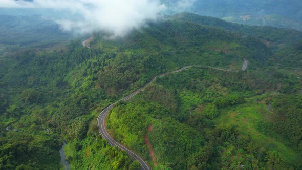 Aerial view over a winding road in the mountains of a tropical forest, Thailand.