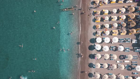 Aerial Top View of Beach with Sunshade and People Swimming at Beautiful Blue Color Sea