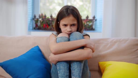 Depressed Schoolgirl Suffering From Loneliness Sitting On Couch At Home