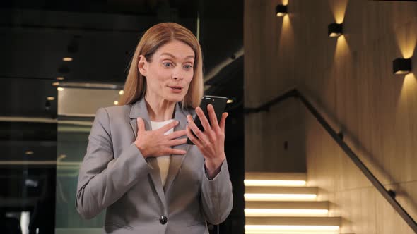 Happy Business Woman Enjoys Success on Mobile Phone in Modern Office Hall