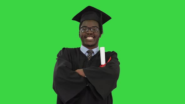 African American Male Student in Graduation Robe Folding Arms with Diploma Looking with a Big Smile