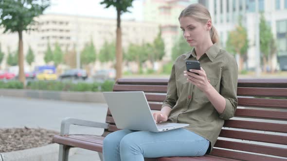Woman Using Smartphone and Laptop while Sitting Outdoor on Bench
