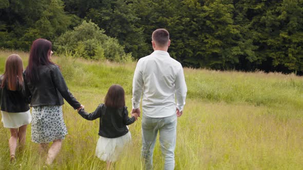 Attractive Pregnant Mother And Father Holding Hands with Her Two Little