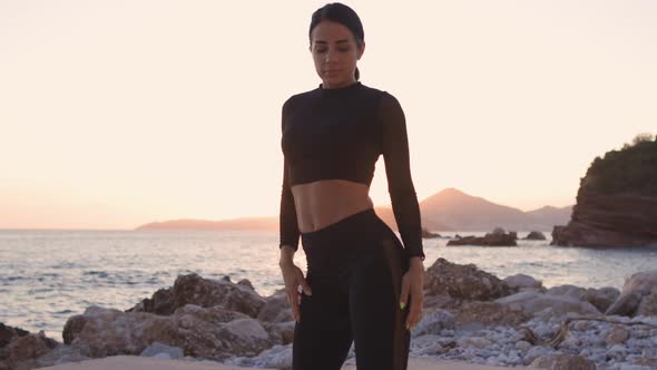 Sporty Woman Posing and Stretching on Beach at Sunset