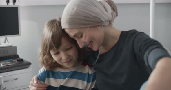 Mother Fighting with Cancer Hugging Little Son While Resting on Hospital Bed