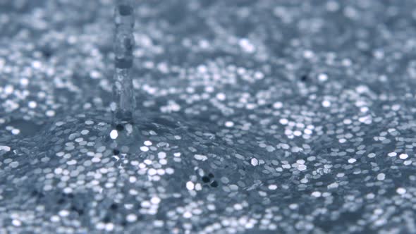 Water drop making ripple on water filled with glitter, Slow Motion