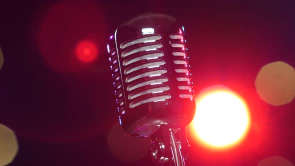 Retro Shiny Microphone Rotating Against Blurry Flashing Lights. Close-up