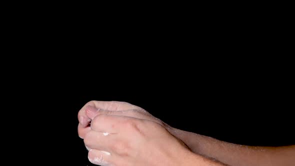 A person rubbing his hands and evenly distributing the chalk powder, isolated on black background. S