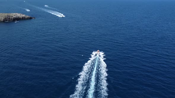 Speedboats trailing in blue waters of Polignano a mar, Italy. Aerial rising