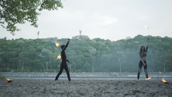 Young Beautiful Girl and Handsome Man in Black Clothes Performing Show with Flame