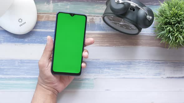 Top View of Man Hand Holding Smart Phone on Table