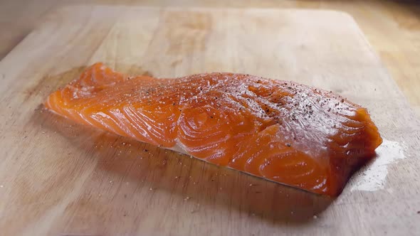 Close Slow Motion Shot of Seasoning a Fresh Piece of Salmon Fillet With Salt Prior to Cooking in the