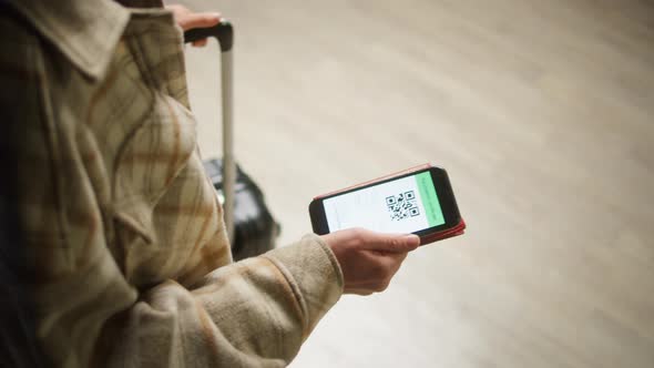 Tourist Showing QR Code on Phone in Airport Terminal