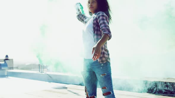 Fashionable young woman on urban rooftop using a smoke grenade