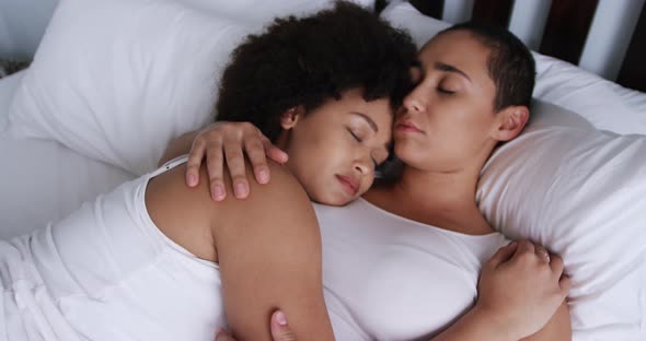 Lesbian couple sleeping on bed in bedroom