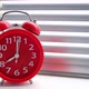 Red alarm clock rang early morning eight clock morning, against background of closed blinds. - VideoHive Item for Sale
