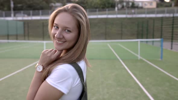 Girl is flirting on the camera on the tennis court