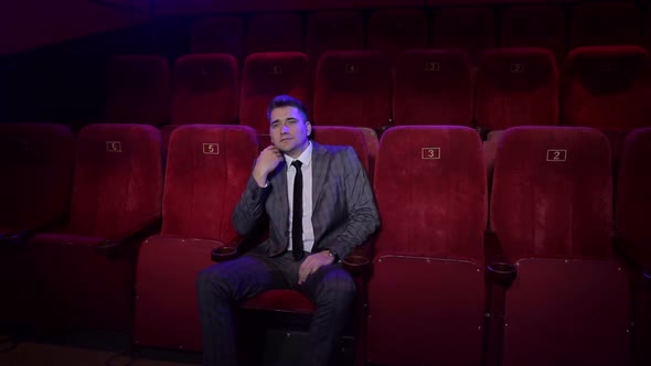 Successful Businessman in a Suit Sitting Alone in a Movie Theater