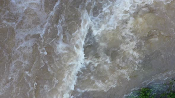 Fast flowing turbulent water with a brown coloration and white foam