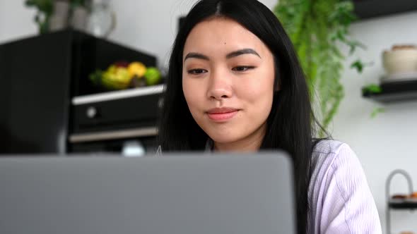 Closeup of Lovely Positive Asian Brunette Girl Designer Freelancer or Student Sits at Kitchen with