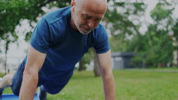 Motivated and Focused Grandfather Makes Push Up with Effort