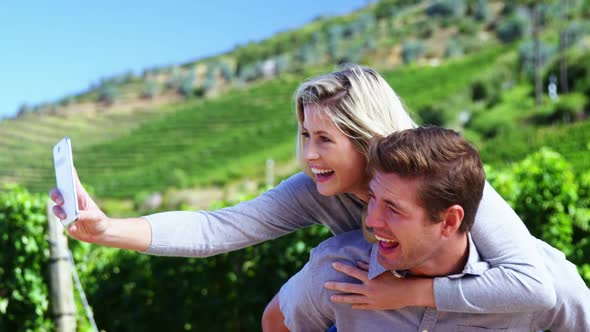 Happy couple taking selfie on mobile phone in vineyard