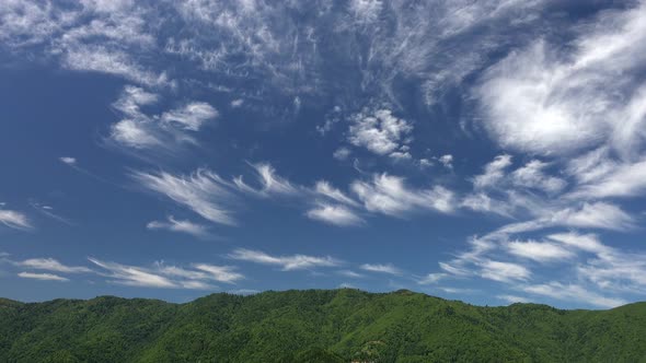 Partly Cirrus Cloud on Forested Mountain Ridge in Blue Sky