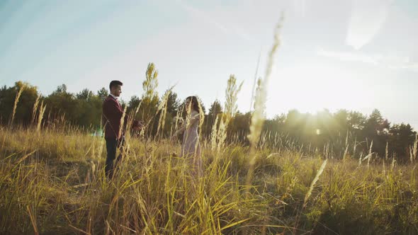 Meeting of Wedding Couple in Love Among Wild Steppe on Sunset