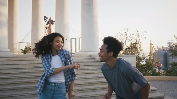 Ethnic Black Friends Smiling and Dancing Against Pillared Observation Deck in Park