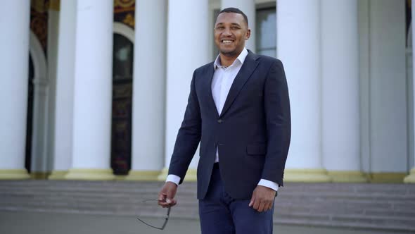 Middle Shot Portrait of Positive Confident Handsome Man in Suit Standing Outdoors Looking at Camera