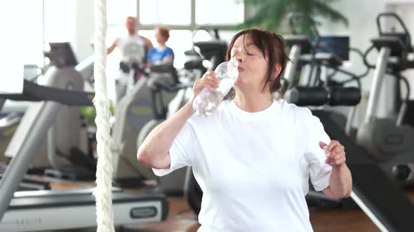 Senior Woman Drinking Water After Fitness Training