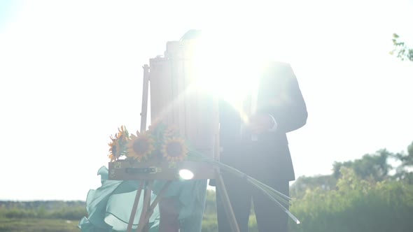 Portrait of Elegant Man in Suit Painting with Woman Standing in Sunbeam Outdoors