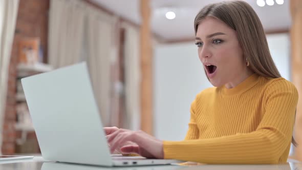 Young Woman Celebrating Success on Laptop