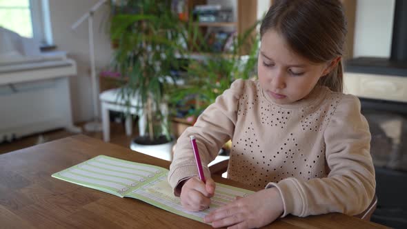 Little girl writing in excercise book, doing homework