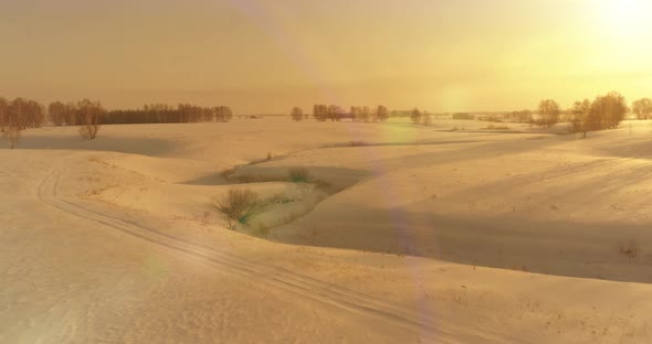 Aerial View of Cold Arctic Field Landscape Trees with Frost Snow Ice River and Sun Rays Over Horizon