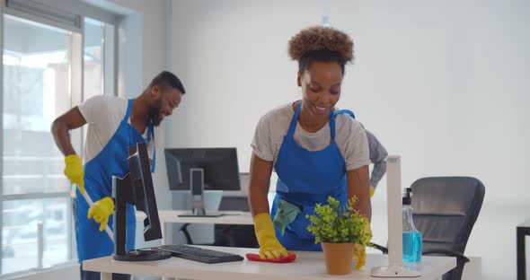 Young Diverse Male and Female Cleaners Wiping Floor and Washing Furniture in Modern Office