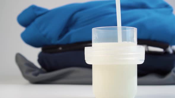 Liquid laundry detergent is poured into a measuring cap