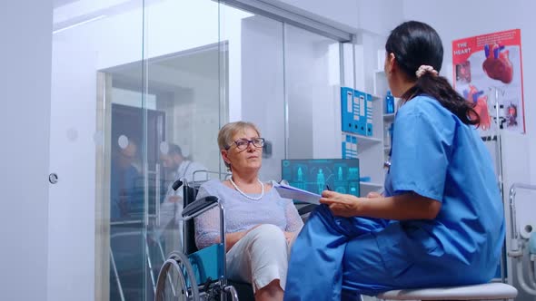 Handicapped Senior Woman in Wheelchair Talking with Nurse