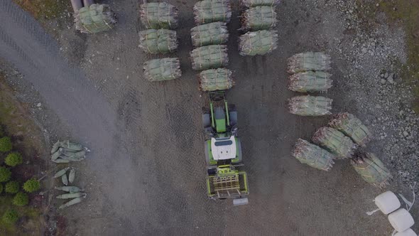 Tractor moves bunch of wrapped Christmas trees for transport; aerial