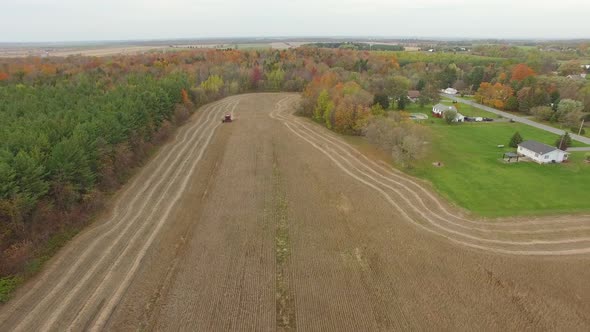 Aerial drone footage flying backwards revealing the city around the farm on harvesting season
