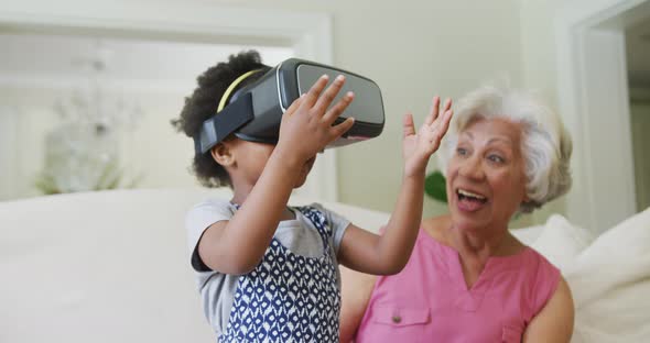 Happy african american grandmother with granddaughter using vr headset in living room