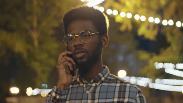 Black Man Talking on Phone Outdoors in Evening