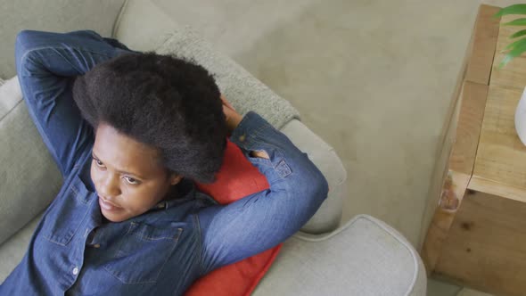 Happy african american woman laying on sofa with eyes closed