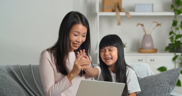 Asian Family Young Mother and Cute Schoolgirl Child Sitting on Couch Making Video Call to Their