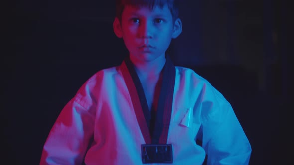 A Little Boy Doing Martial Arts in the Dark with Neon Lighting  Standing in the Position