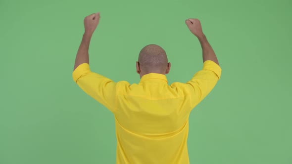 Rear View of Happy Bald Businessman with Fists Raised