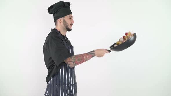 Side View of Professional Chef Tossing Vegetables in a Wok Against White Background